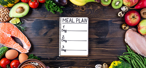 meal plan notebook surrounded by fresh fruits vegetables and salmon for healthy eating meal prep for 5 days