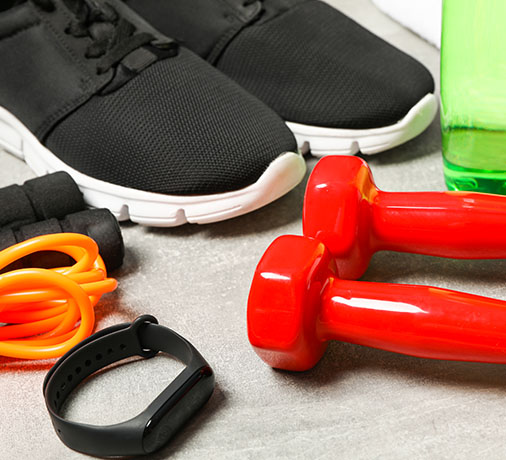 black athletic shoes with red dumbbells water bottle fitness gear and accessories for a workout routine to achieve goals in 6 weeks