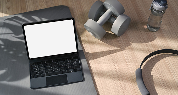 a top view of a workout setup featuring a laptop a dumbbell a water bottle and a pair of headphones with emphasis on fitness and exercise 4 ways to stay active