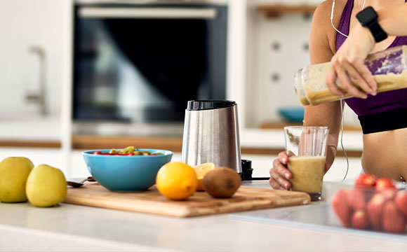 woman preparing smoothie in kitchen with fruits and blender for healthy living and nutrition 3 ingredients smoothie