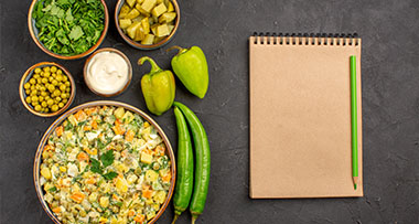 colorful vegetable salad with fresh greens and condiments arranged around a blank notepad and green pencil perfect for writing 11 recipe ideas