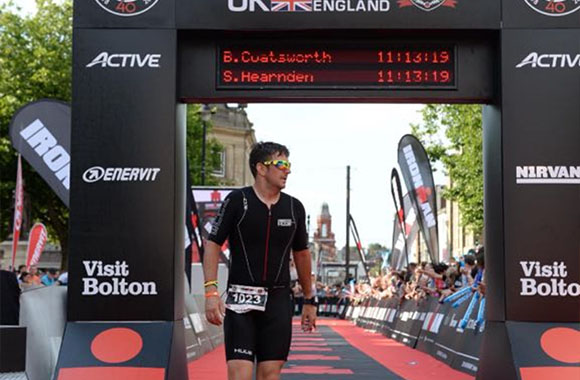 male triathlete crossing finish line in Bolton with race time displayed promoting endurance 8 events