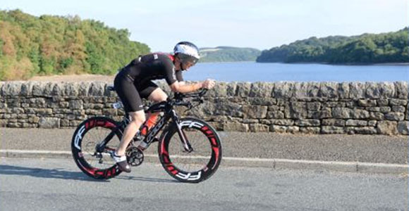 man cycling on road near water with trees in background six distinct features of bike triathlon